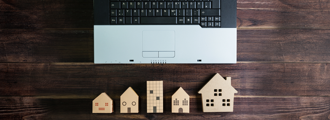 Modelos de casas de madera al lado de un ordenador portátil