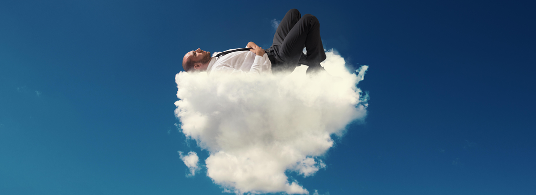 Un hombre con traje dormido sobre una nube esponjosa