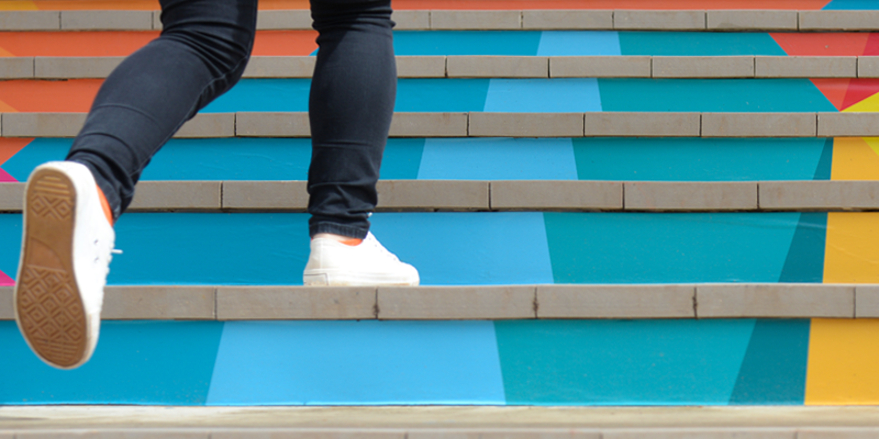 Una persona sube unas escaleras de colores